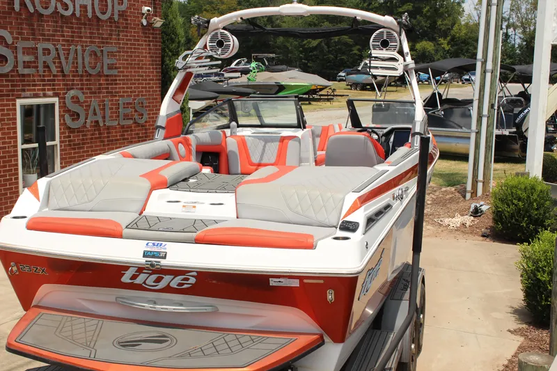 Slide: The Image of 2020 Tigé 23ZX boat with red and gray seating, displayed at a dealership. - 4