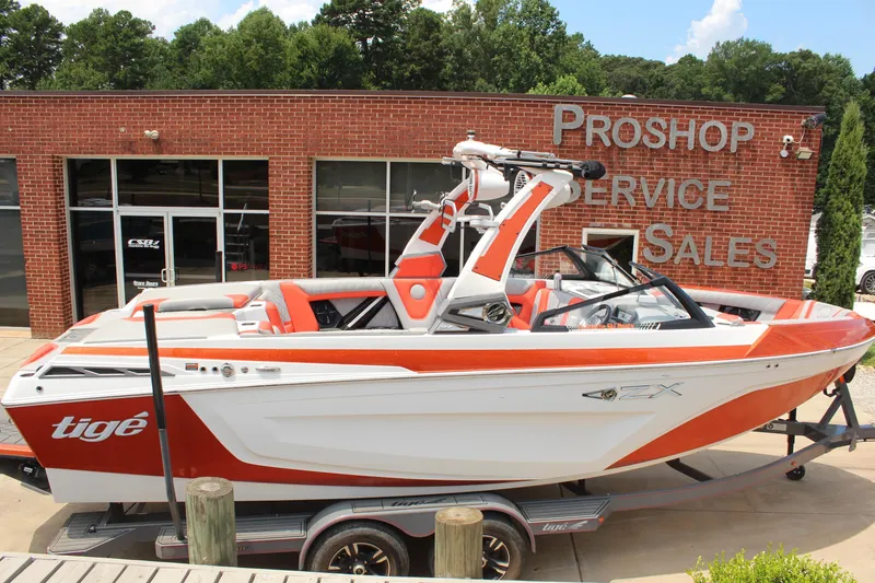 Slide: The Image of 2020 Tigé 23ZX boat in front of a pro shop, featuring orange and white design. - 5