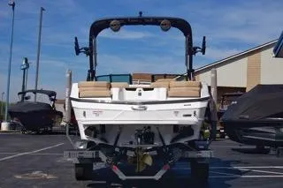 Slide: The Image of 2025 MasterCraft XT20 boat, rear view, parked outdoors under clear blue sky. - 3