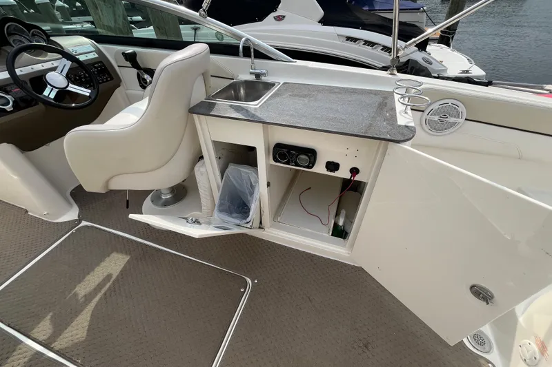 Slide: The Image of 2013 Sea Ray 280 Sundeck interior with helm, sink, and storage compartments. - 14