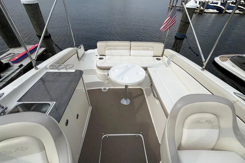 Slide: The Image of 2013 Sea Ray 280 Sundeck interior with seating, table, and sink at marina. - 26