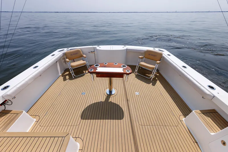 Slide: The Image of 2023 Henriques 42 Express Hardtop boat deck with chairs and table on calm water. - 20