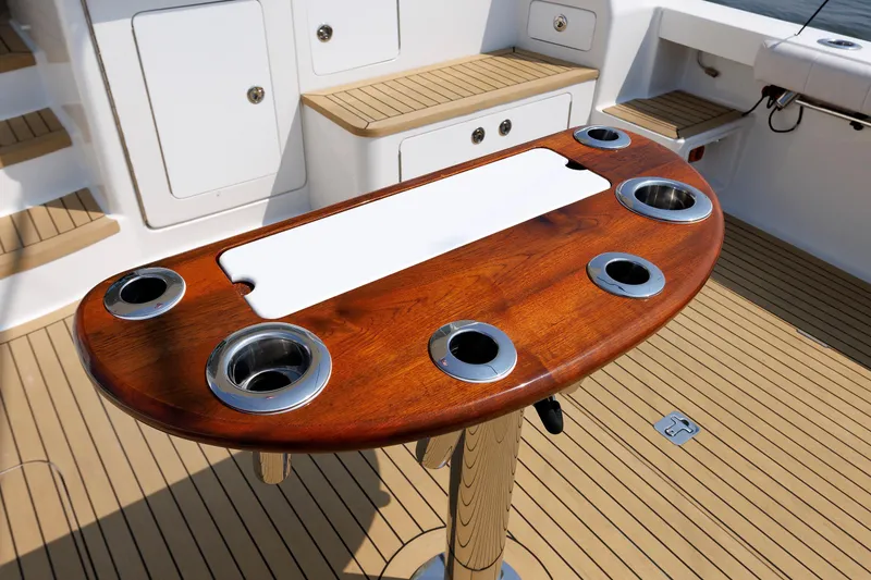 Slide: The Image of Henriques 42 Express Hardtop 2023 boat deck with wooden table and cup holders. - 22