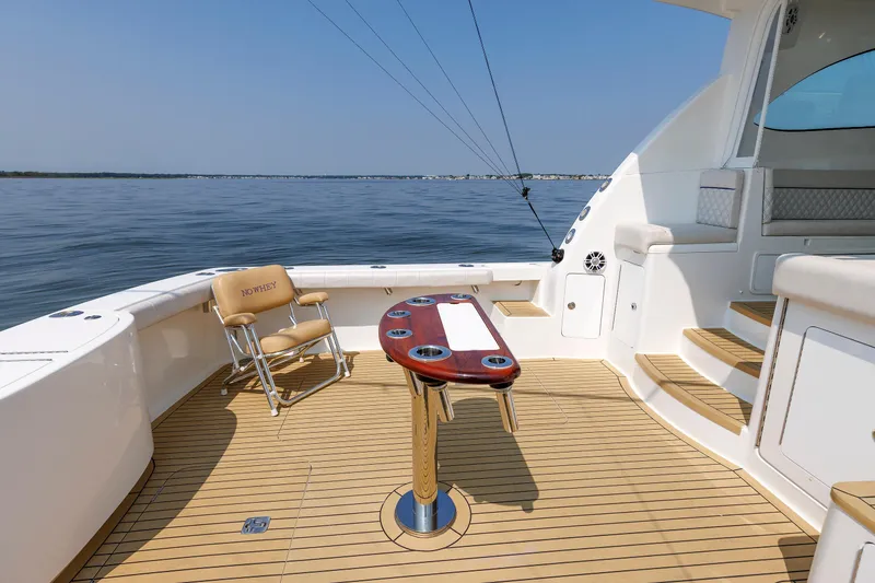 Slide: The Image of 2023 Henriques 42 Express Hardtop boat deck with fishing chair and table on calm water. - 24