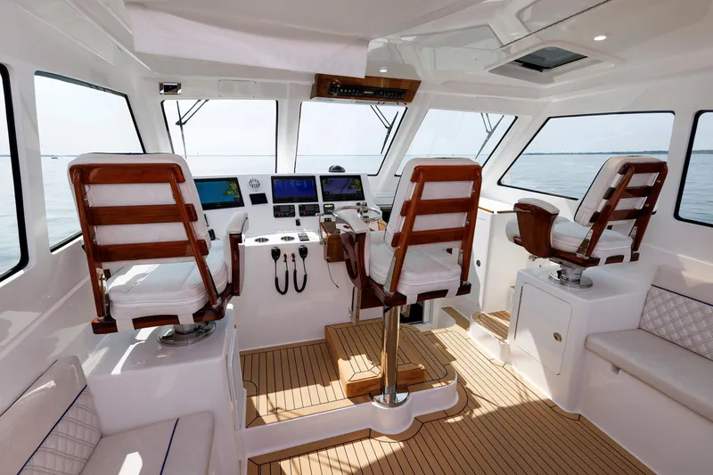 Slide: The Image of 2023 Henriques 42 Express Hardtop interior with helm, wooden seats, and navigation equipment. - 29