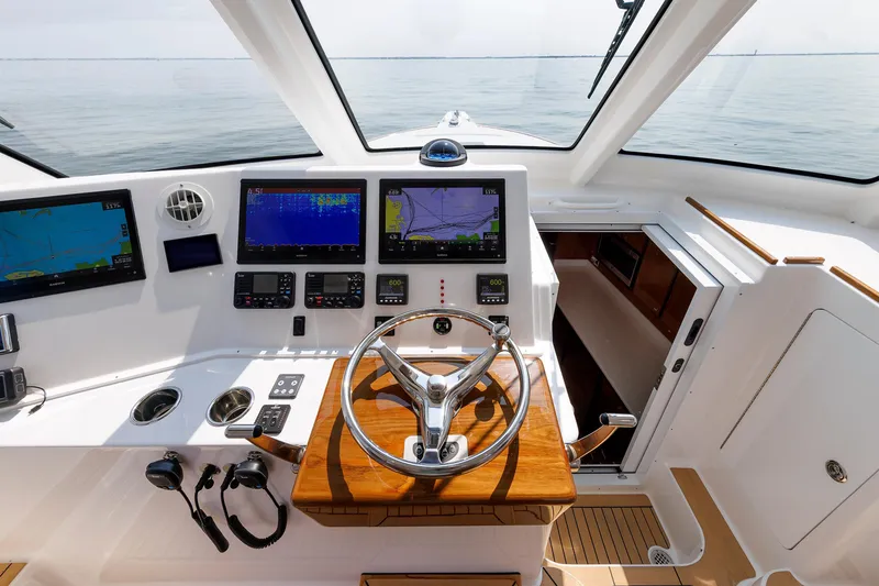 Slide: The Image of 2023 Henriques 42 Express Hardtop helm with advanced navigation displays and wooden steering wheel. - 39