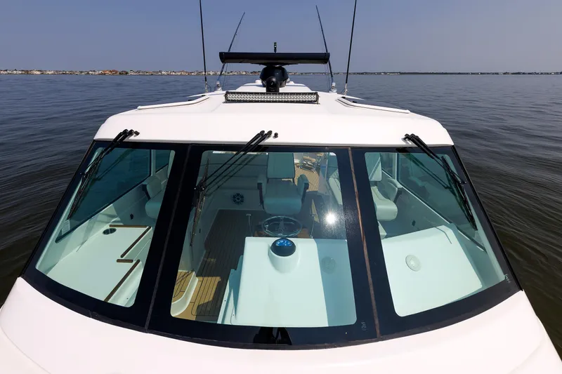Slide: The Image of 2023 Henriques 42 Express Hardtop boat on calm water, showcasing sleek design and spacious interior. - 58
