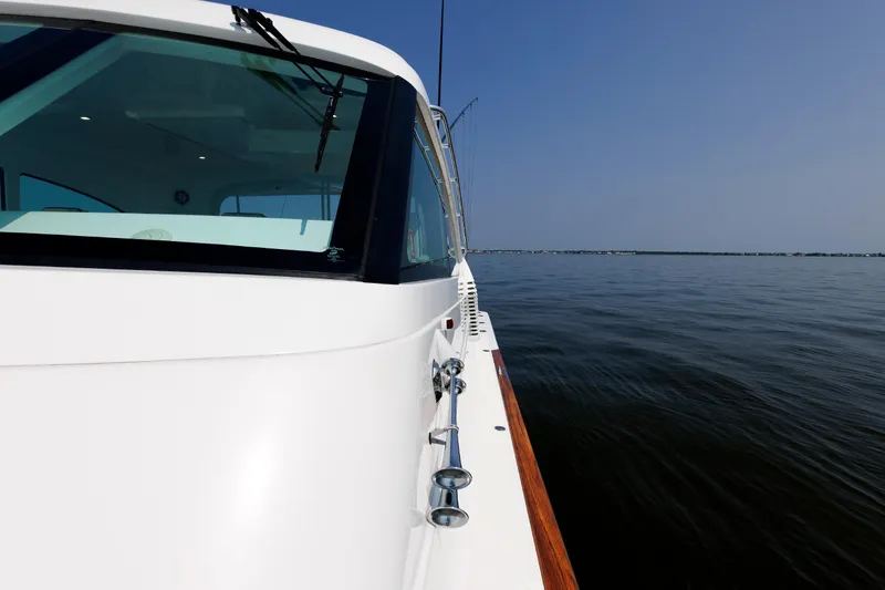 Slide: The Image of 2023 Henriques 42 Express Hardtop yacht cruising on calm waters under clear blue sky. - 59