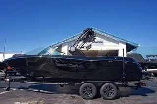 The Image of 2025 MasterCraft NXT23 boat on trailer, parked outside a marine dealership. - 1