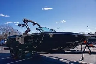 Slide: The Image of 2025 MasterCraft NXT23 boat on trailer under clear blue sky. - 5