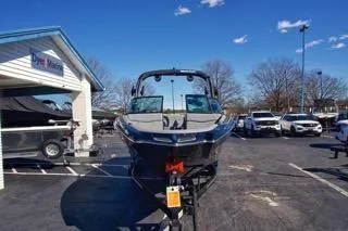 Slide: The Image of 2025 MasterCraft NXT23 boat on trailer in parking lot, clear sky background. - 6