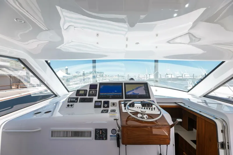 Slide: The Image of 2018 Hatteras GT45X Flybridge helm with navigation screens and steering wheel, dockside view. - 17