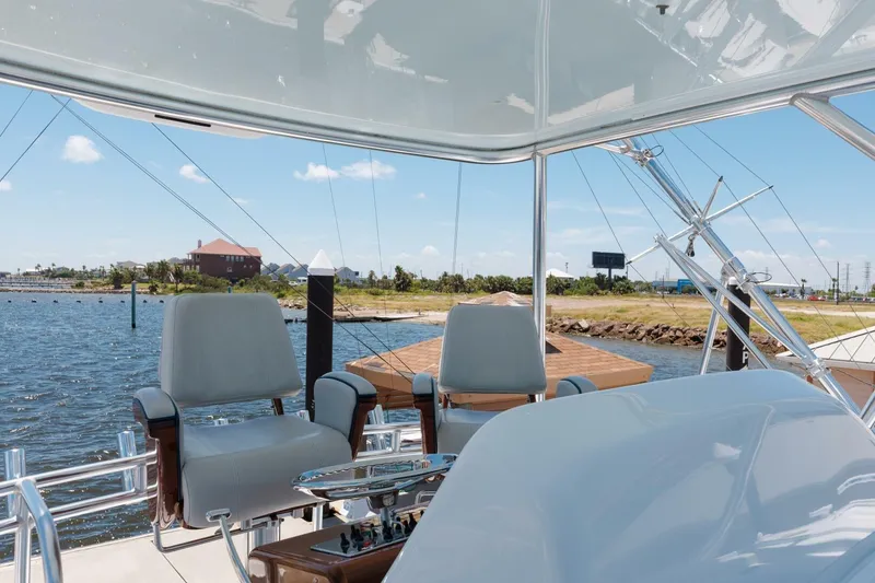 Slide: The Image of Flybridge view of 2018 Hatteras GT45X yacht with helm chairs and water backdrop. - 27