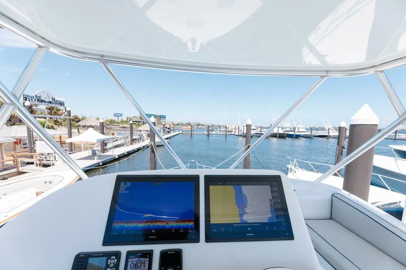 Slide: The Image of Flybridge view from 2018 Hatteras GT45X, featuring navigation screens and marina backdrop. - 30