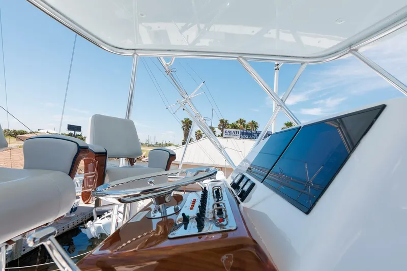 Slide: The Image of 2018 Hatteras GT45X Flybridge helm with modern controls and seating, under clear blue sky. - 31