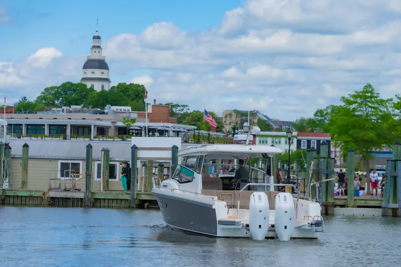 Slide: The Image of Nimbus W11 #46 boat docked in scenic harbor with historic architecture, 2025 model. - 12
