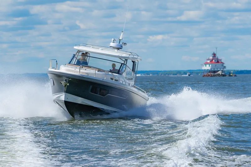 Slide: The Image of Nimbus W11 #46 boat cruising on open water, 2025 model, with lighthouse in background. - 4