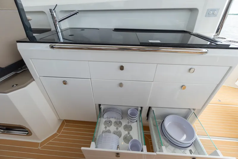 Slide: The Image of Modern yacht kitchen with open drawers, showcasing dishes and glassware, Nimbus W11 #46, 2025 model. - 54