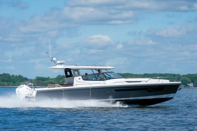 Slide: The Image of 2025 Nimbus W11 #46 motorboat cruising on a sunny day, with lush greenery in the background. - 60