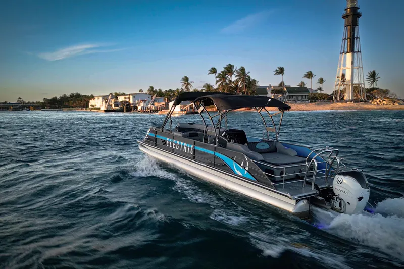 Slide: The Image of 2025 Vision Marine Technologies V30 electric boat cruising near a lighthouse at sunset. - 2