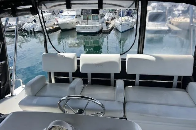 Slide: The Image of 1997 Silverton 351 Sedan Cruiser interior with white seating, overlooking marina. - 10