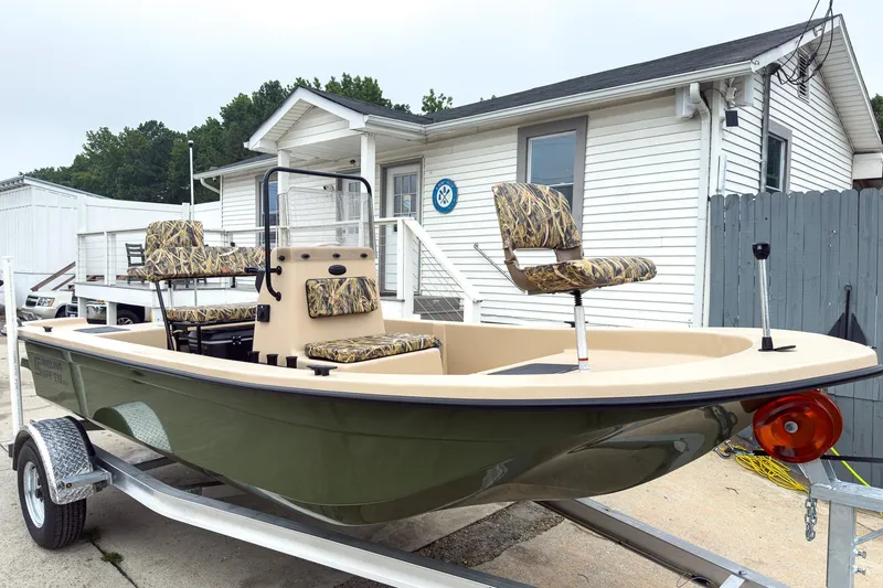 The Image of 2026 Carolina Skiff E18 JVX CC Sportsman boat on trailer, parked outside a building. - 0