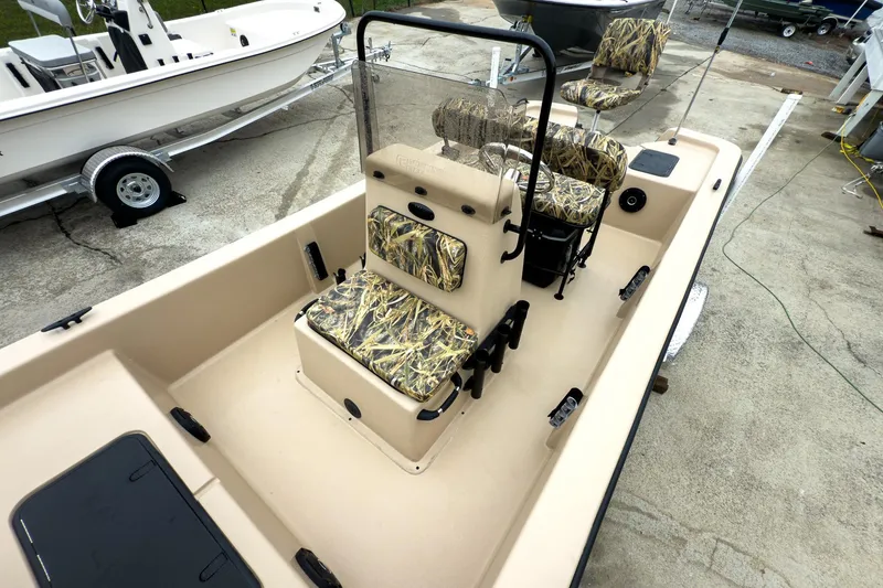 Slide: The Image of 2026 Carolina Skiff E18 JVX CC Sportsman boat with camo seating, docked on concrete. - 19