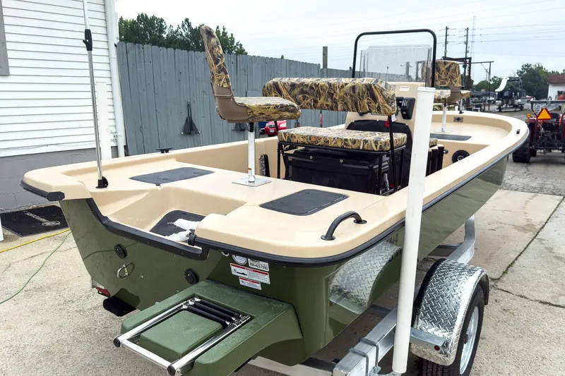 Slide: The Image of 2026 Carolina Skiff E18 JVX CC Sportsman boat on trailer, featuring camo seats. - 2