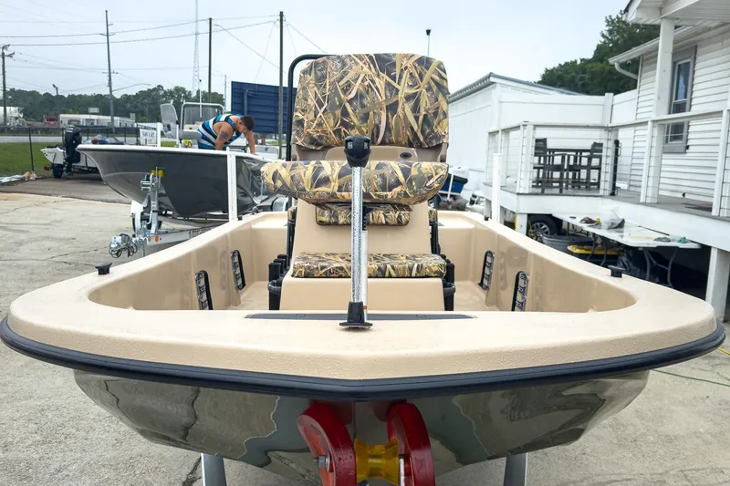 Slide: The Image of 2026 Carolina Skiff E18 JVX CC Sportsman boat with camo seating, displayed outdoors. - 27