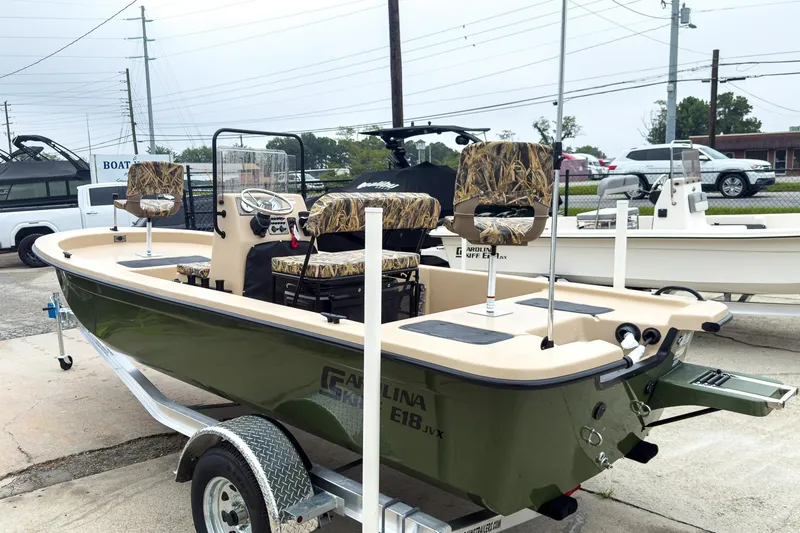 Slide: The Image of 2026 Carolina Skiff E18 JVX CC Sportsman boat on trailer, featuring camo seats. - 3