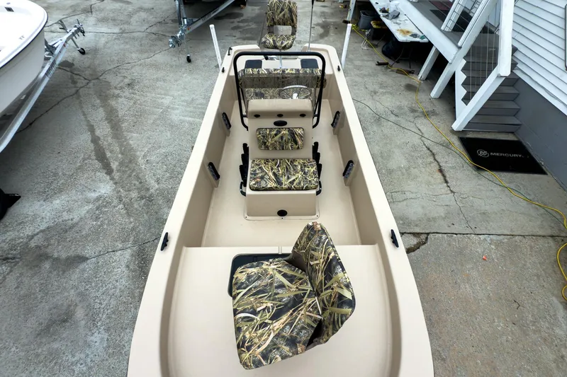 Slide: The Image of 2026 Carolina Skiff E18 JVX CC Sportsman boat with camo seats, docked on concrete. - 34