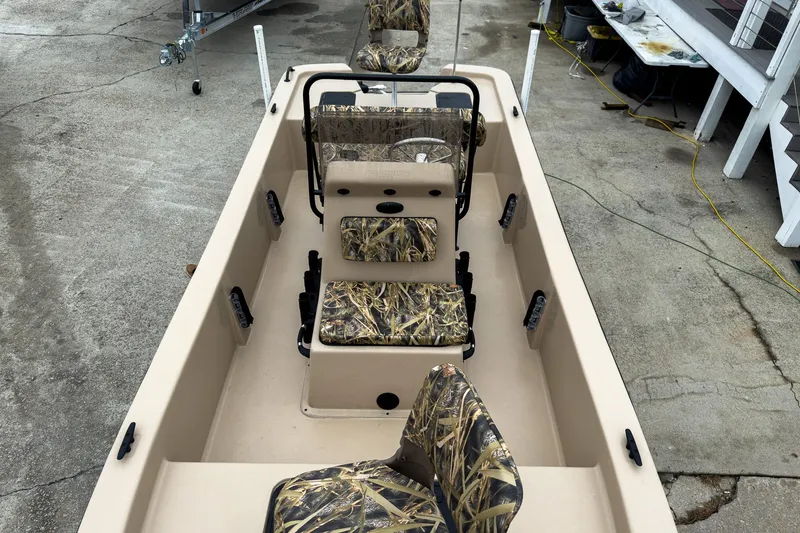 Slide: The Image of 2026 Carolina Skiff E18 JVX CC Sportsman boat with camouflage seating, docked on concrete. - 35