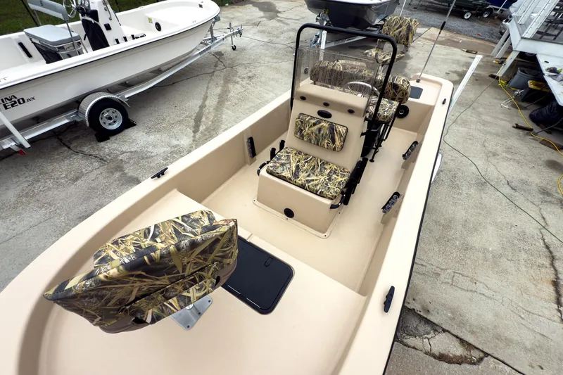 Slide: The Image of 2026 Carolina Skiff E18 JVX CC Sportsman boat with camouflage seating, parked on a trailer. - 5