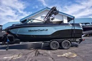 The Image of 2025 MasterCraft XT22 T boat on trailer, parked outdoors under blue sky. - 1