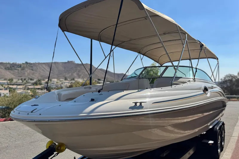 Slide: The Image of 2000 Sea Ray 240 Sundeck boat with canopy, parked on trailer, scenic background. - 3
