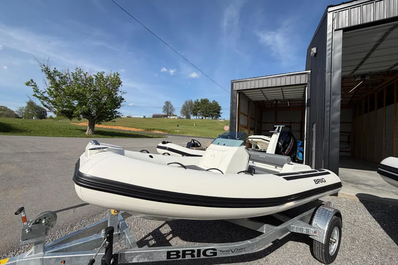 Slide: The Image of 2026 Brig Eagle 4 inflatable boat on trailer outside a garage under clear blue sky. - 8