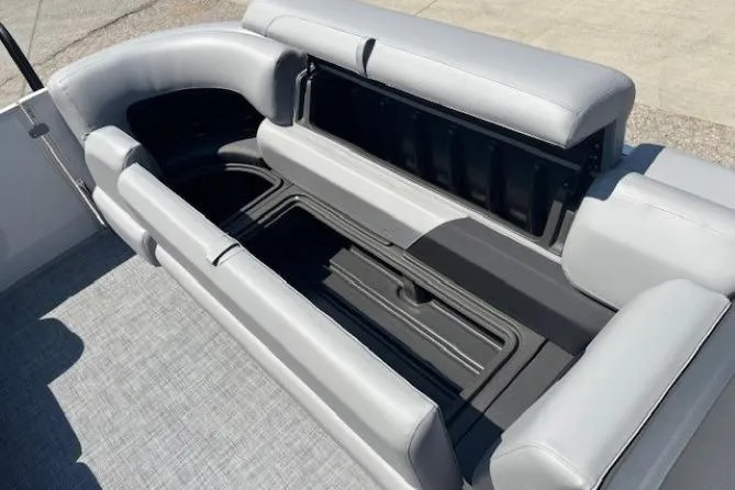 Slide: The Image of 2025 Sun Tracker Party Barge 20 DLX with open storage compartment and gray seating. - 12