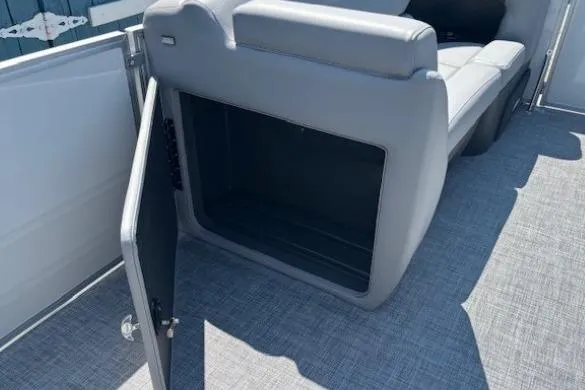 Slide: The Image of 2025 Sun Tracker Party Barge 20 DLX storage compartment with open door on deck. - 16