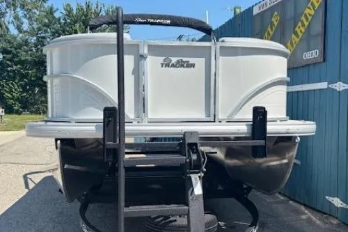 Slide: The Image of 2025 Sun Tracker Party Barge 20 DLX pontoon boat on trailer, parked outdoors. - 2