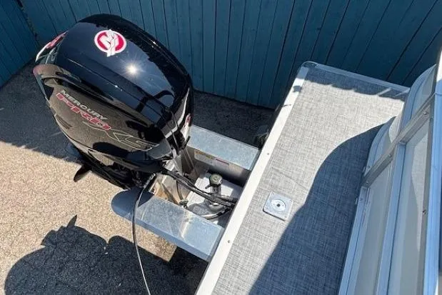 Slide: The Image of 2025 Sun Tracker Party Barge 20 DLX with powerful outboard motor, docked by blue fence. - 28