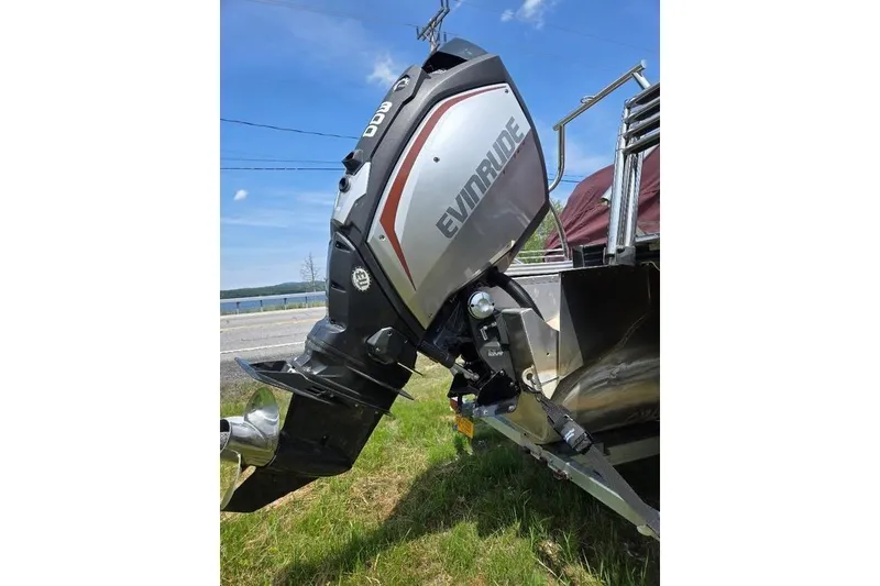 Slide: The Image of 2019 Manitou Legacy 25 RFXW with Evinrude outboard motor, parked on grass. - 13