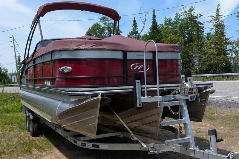 Slide: The Image of 2019 Manitou Legacy 25 RFXW pontoon boat on trailer, parked outdoors. - 32