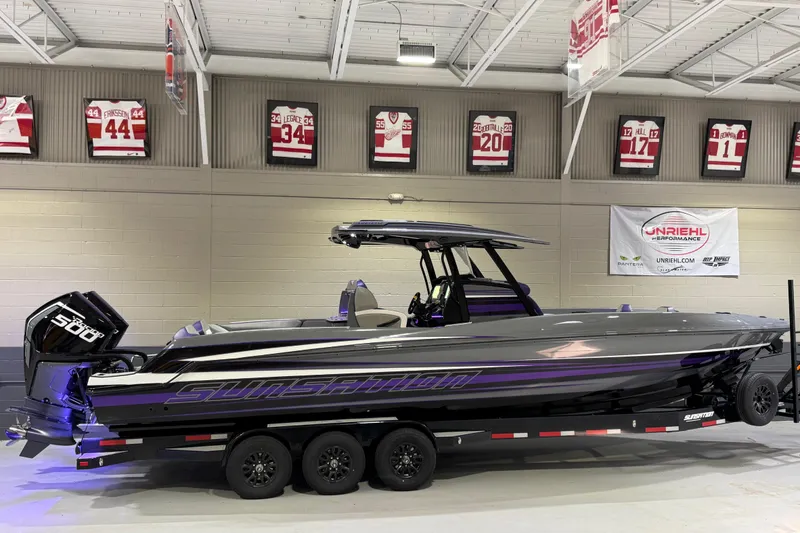 Slide: The Image of 2026 Sunsation 32 CCX boat on trailer in indoor showroom with sports memorabilia. - 2