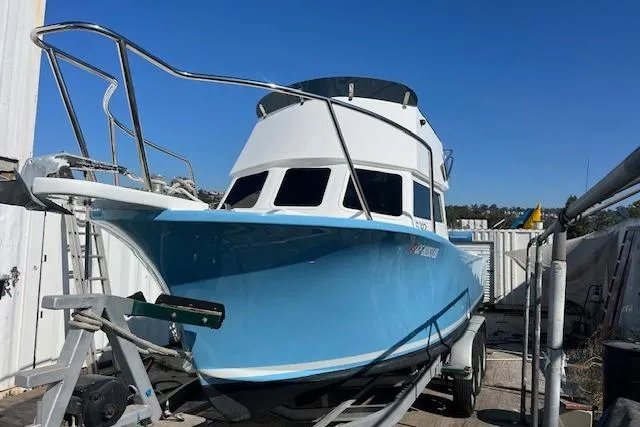 The Image of 1971 Mariners BAJA 30 boat with blue hull on trailer, docked outdoors. - 1