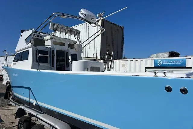 Slide: The Image of 1971 Mariners BAJA 30 boat with blue hull, docked near shipping containers. - 13