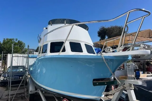 Slide: The Image of 1971 Mariners BAJA 30 boat with blue hull, docked outdoors under clear sky. - 3