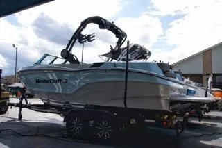 The Image of 2025 MasterCraft XT22 T boat on trailer, sleek design, under cloudy sky. - 1