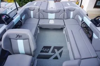 Slide: The Image of 2025 MasterCraft XT22 T boat interior with gray seating and logo on floor. - 10