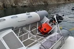 Slide: The Image of Inflatable boat docked near rocky shore, featuring an outboard motor and orange fuel tank. - 53