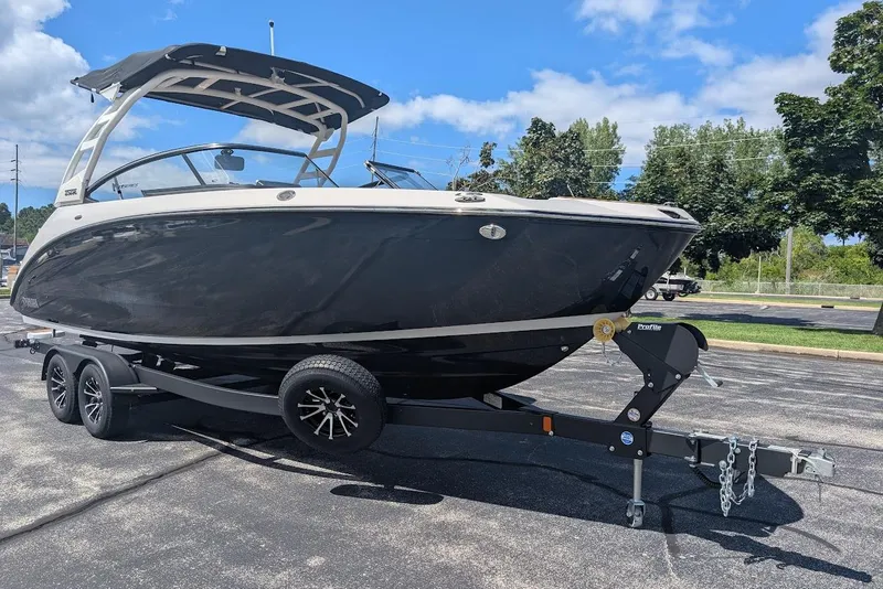 The Image of 2024 Yamaha Boats 252SE on trailer, sleek black design, parked outdoors under blue sky. - 0
